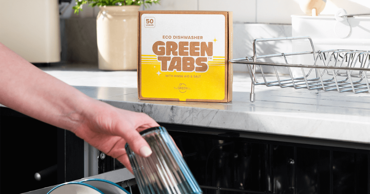 dishwasher greentabs on kitchen counter with hand placing glass in dishwasher