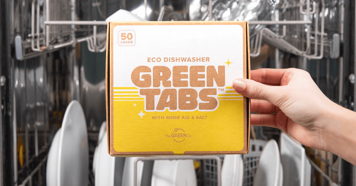 eco friendly dishwasher detergent being held beside open dishwasher