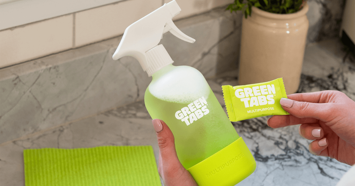 eco friendly multipurpose spray greentabs™ in glass forever bottle being held in hand