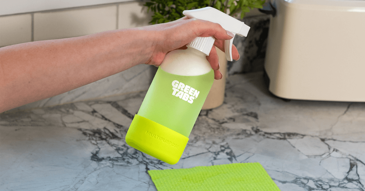 multipurpose greentabs in glass forever bottle being spray on kitchen counter