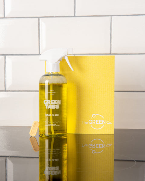 Yellow GreenTab kitchen degreaser in forever bottle with yellow cellulose dish cloth sitting on kitchen hob 