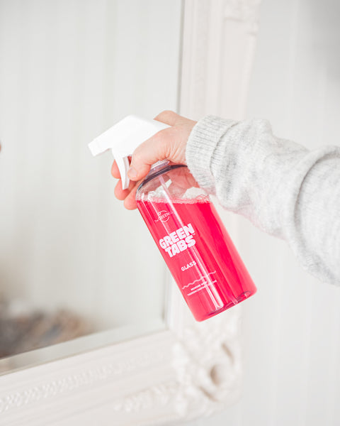 Pink Glass cleaner GreenTab in forever bottle being used to clean wood burner glass in lifestyle product shot