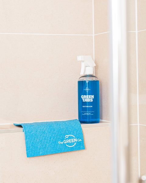 Blue bathroom cleaner in reusable bottle and blue cellulose cloth