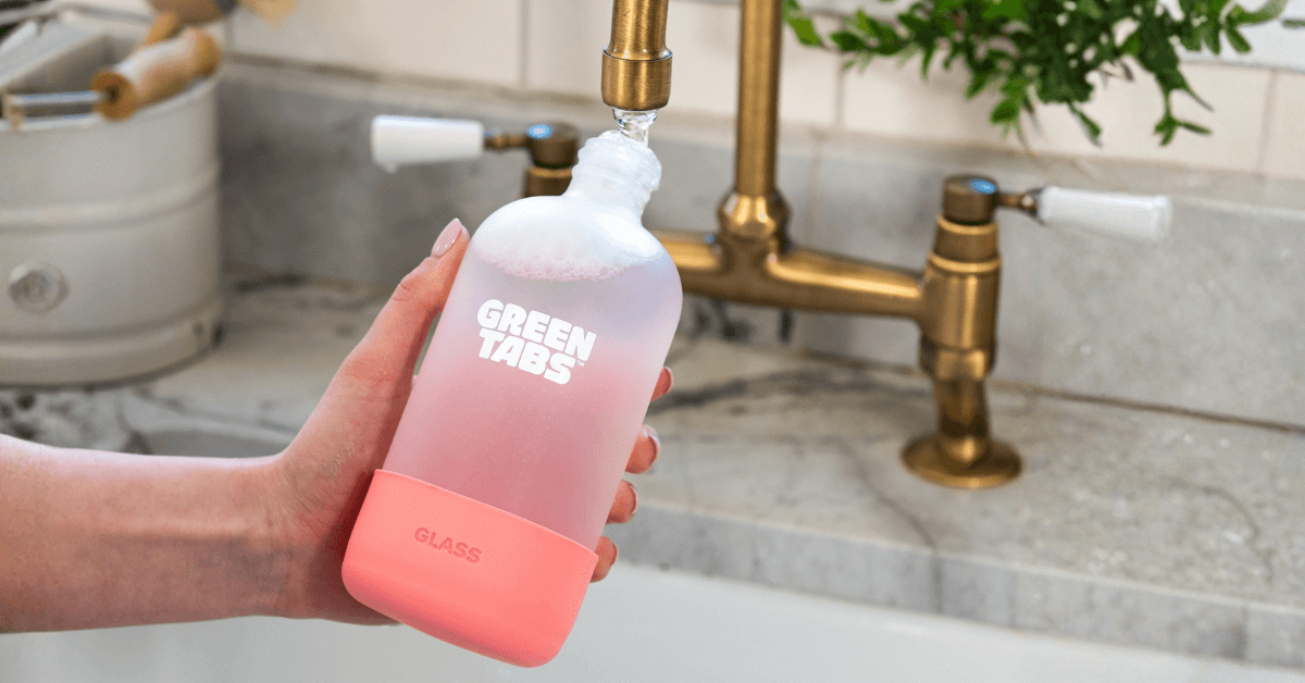 refillable glass cleaning spray bottle being filled with tap water to create spray