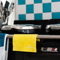 Yellow Cellulose Dish Cloth draped over the stove handles of a blue and white tiled kitchen