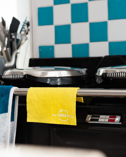 Yellow Cellulose Dish Cloth draped over the stove handles of a blue and white tiled kitchen