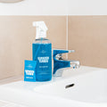 Blue Bathroom Cleaner GreenTab in Forever Bottle and Blue GreenTab in packaging sitting next to tap on Bathroom sink