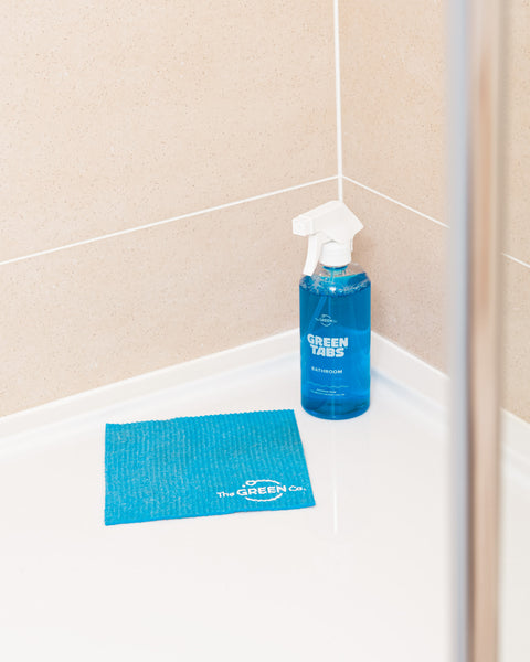 Blue Bathroom Cleaner GreenTab in Forever Bottle and Blue Cellulose Dish Cloth sitting on Shower Floor