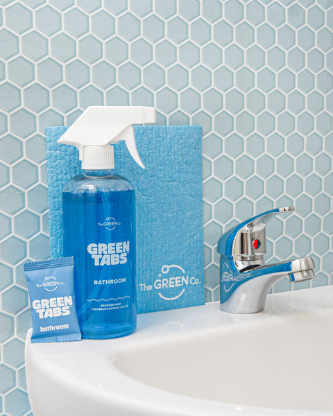 Blue Bathroom Cleaner GreenTab in Forever Bottle, Bathroom Cleaner GreenTab in packaging and Blue Cellulose dish cloth sitting on Bathroom sink next the tap