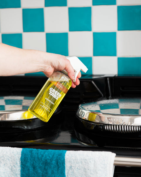 yellow kitchen degreaser GreenTab in forever bottle being used to clean a blue and white kitchen tile