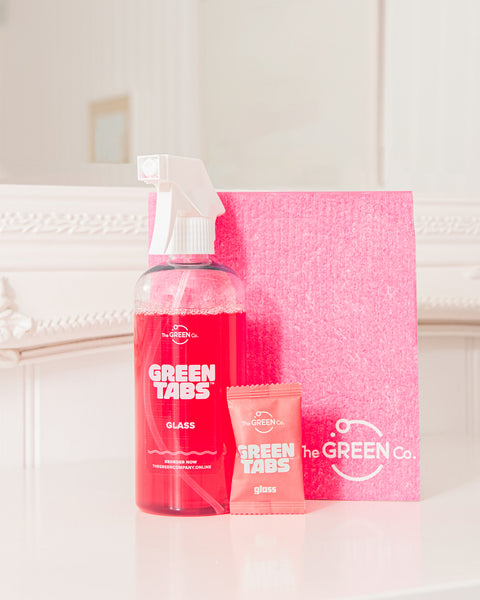 pink GreenTabs glass cleaner, pink cellulose dish cloth and pink GreenTab sitting infront of mirror backdrop