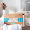 Green Company laundry strips fresh linen 64 pack sitting in a wicker laundry basket with white bed linen