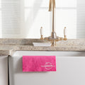 Pink Cellulose Dish Cloth hanging over the edge of a ceramic sink with golden tap