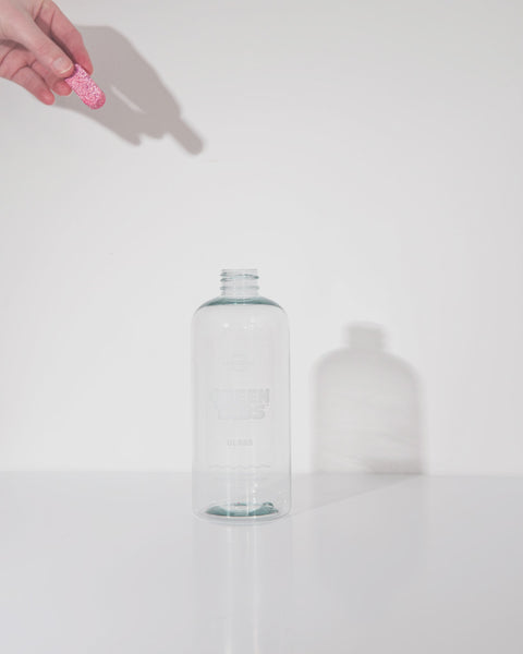 Gif video that shows a hand dropping in a Glass Cleaner GreenTab into a forever bottle infront of white backdrop, Gif showcasing how GreenTab dissolves